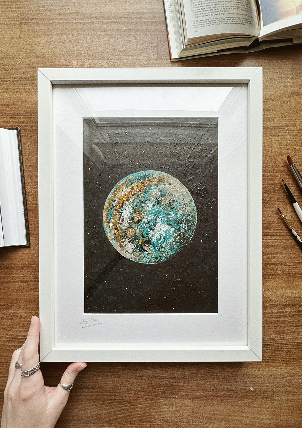 A framed original artwork depicting a stylized version of Jupiter, with a focus on its planetary features rather than its moons, presented in a wooden frame.