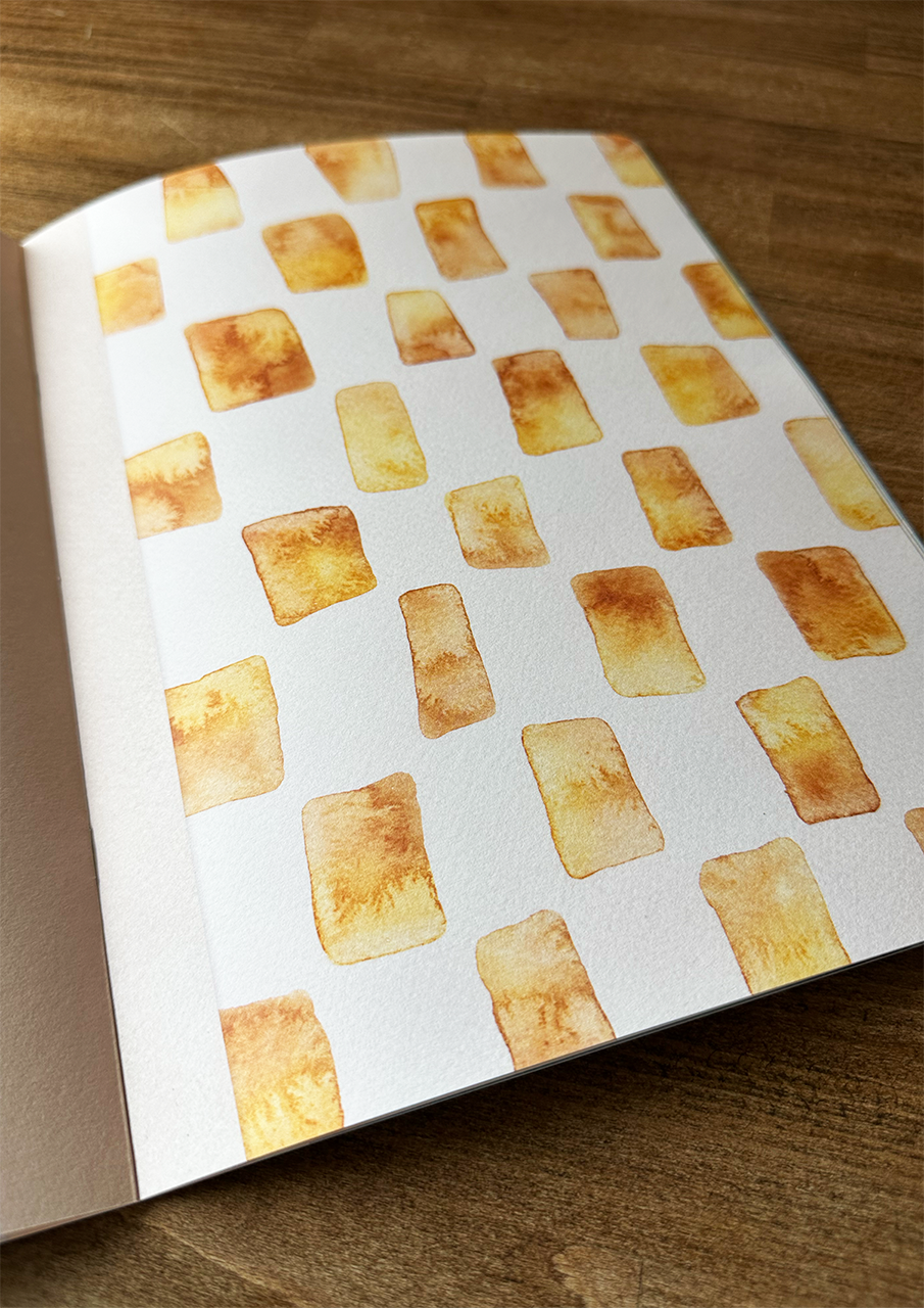 Book with watercolor pattern of rectangular shapes on a wooden surface