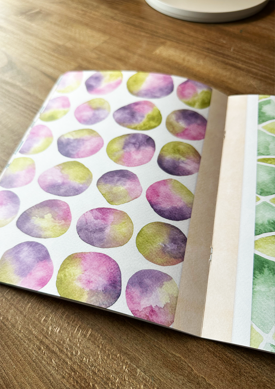 Open notebook with watercolor pattern on a wooden surface
