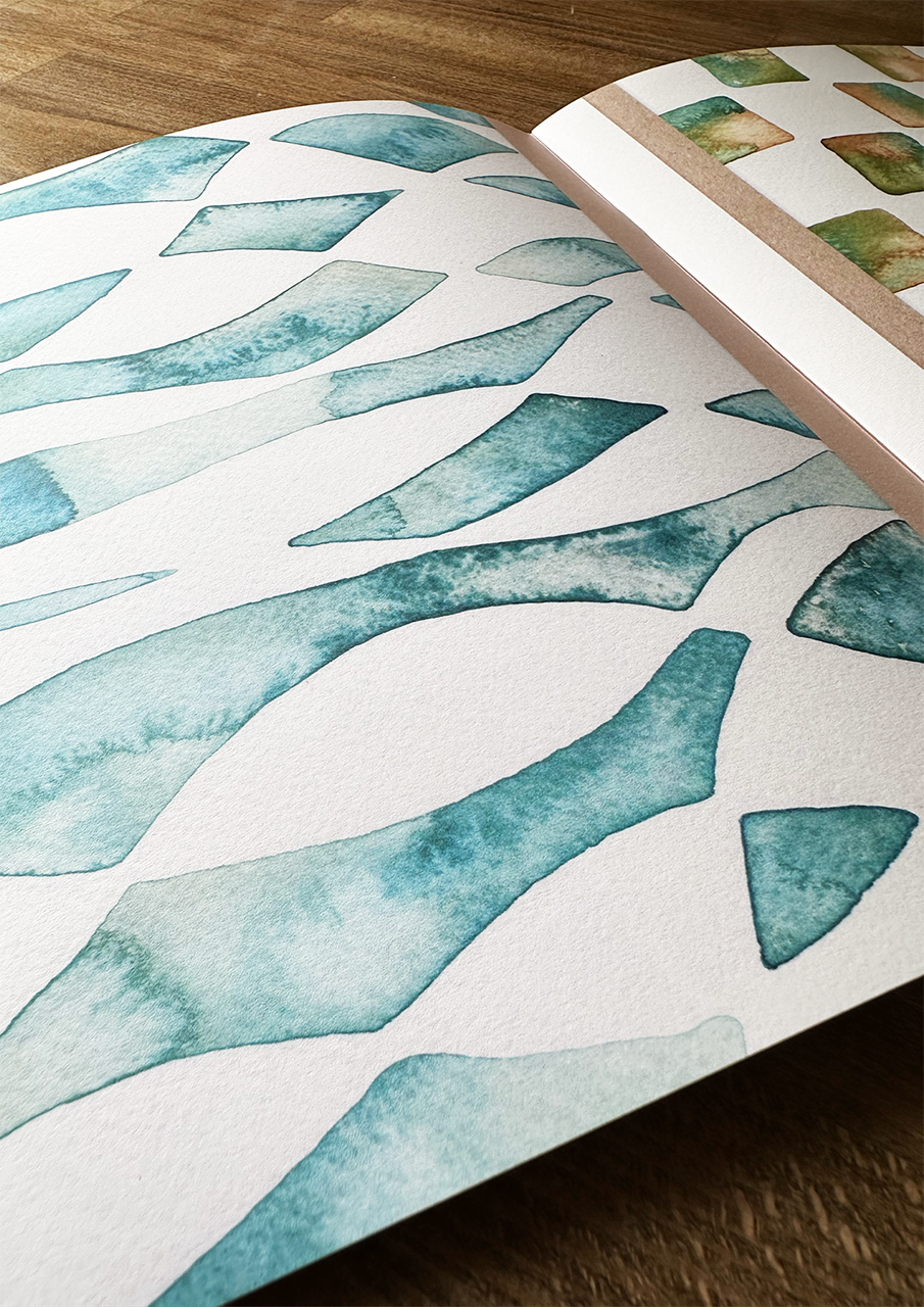 Open book with watercolor design of blue abstract shapes on a white background.