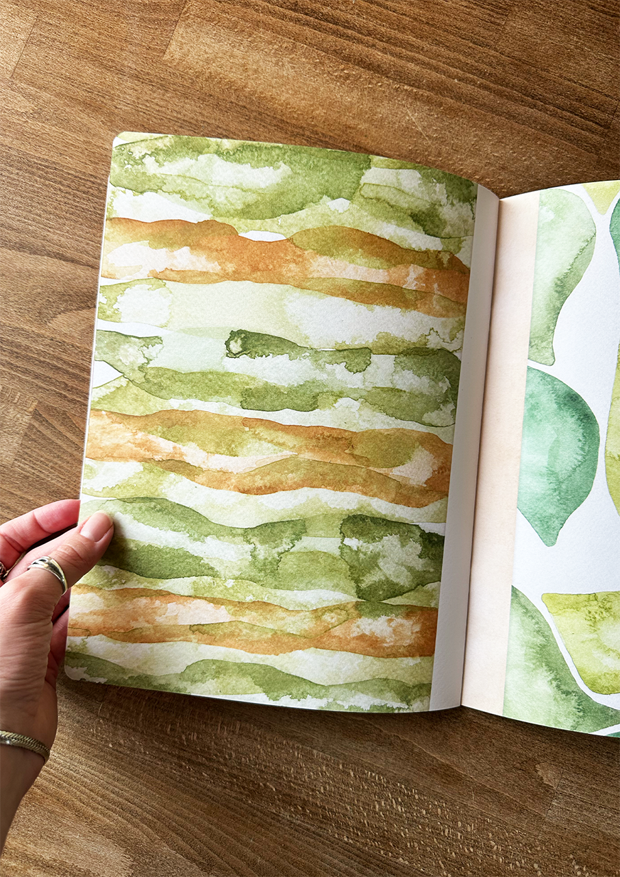 Open book with watercolor pages on a wooden surface