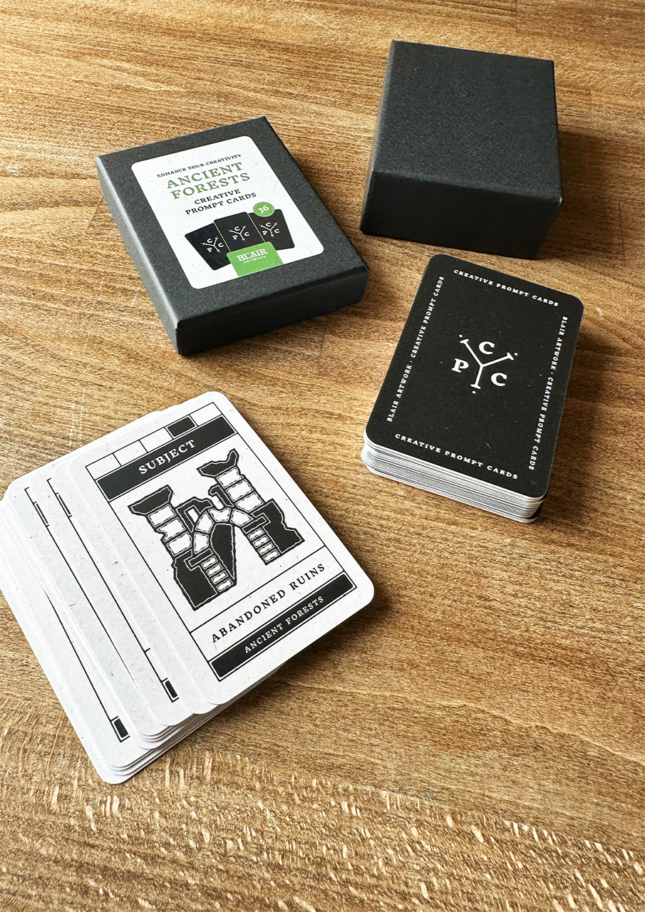 Three black and white playing cards with a logo on a wooden surface