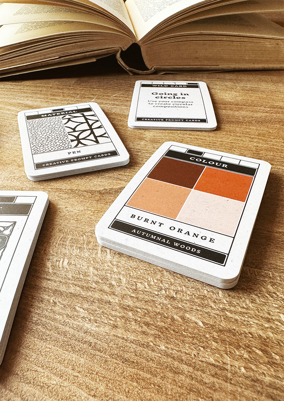 Color swatch cards on a wooden surface with an open book in the background