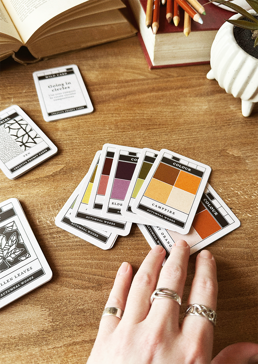 Color swatch cards on a wooden table with a hand reaching for one