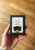 Hand holding a box of 'Dark Academia' creative prompt cards on a wooden surface