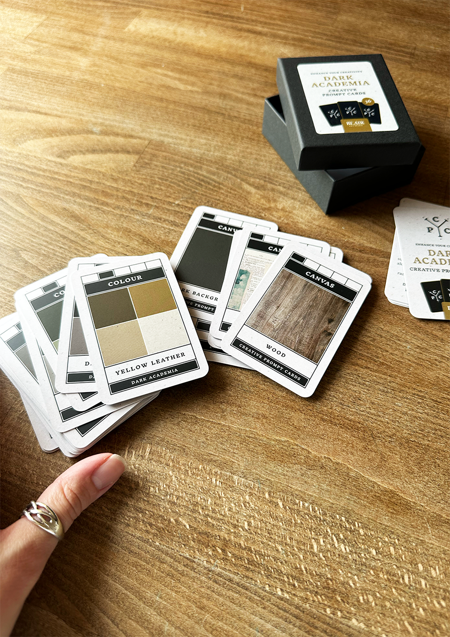 Color swatch cards on a wooden surface with a hand reaching out