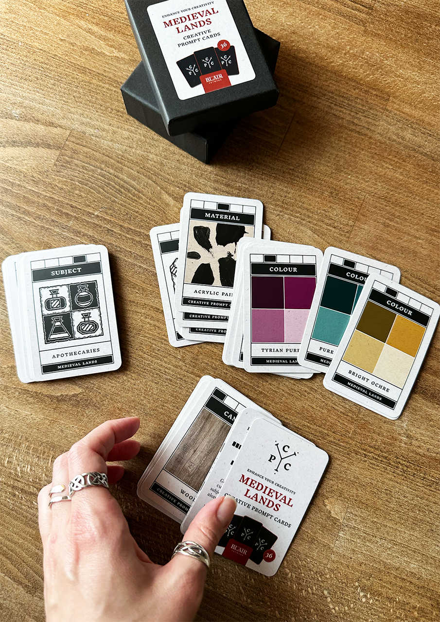 Collection of cards on a wooden surface with a hand holding one card.