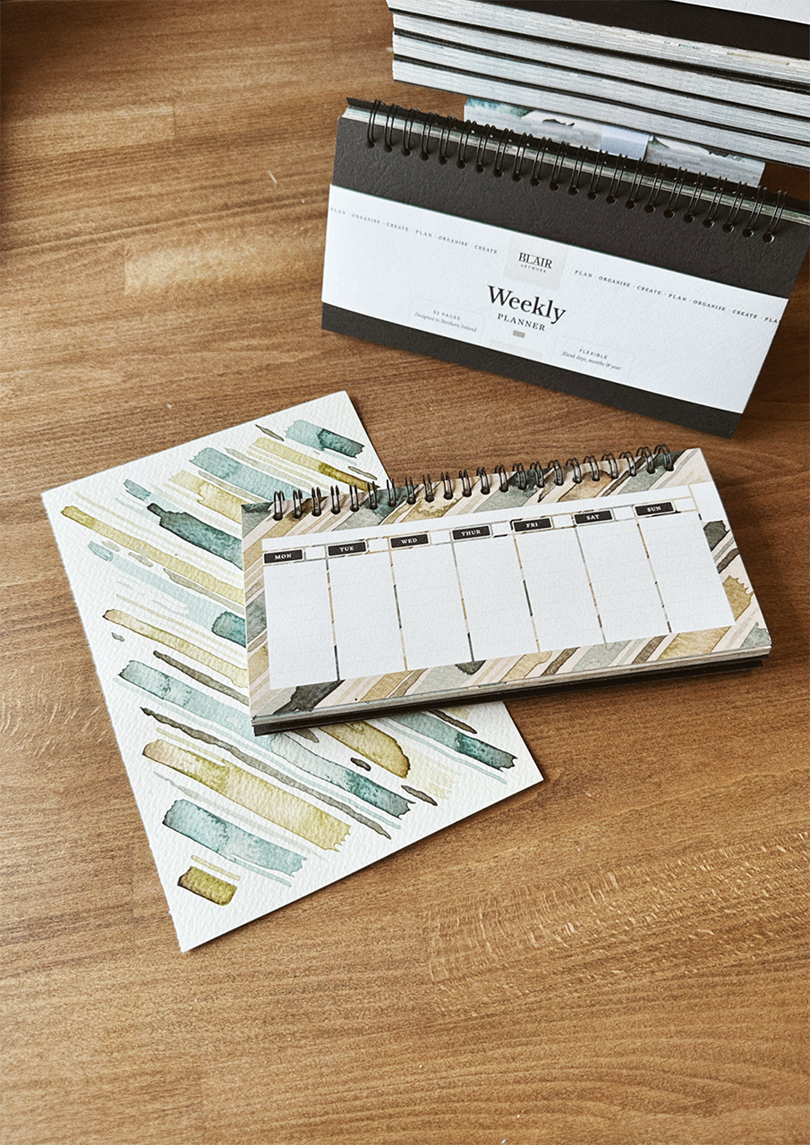 A desktop weekly planner, displayed on a wooden surface.