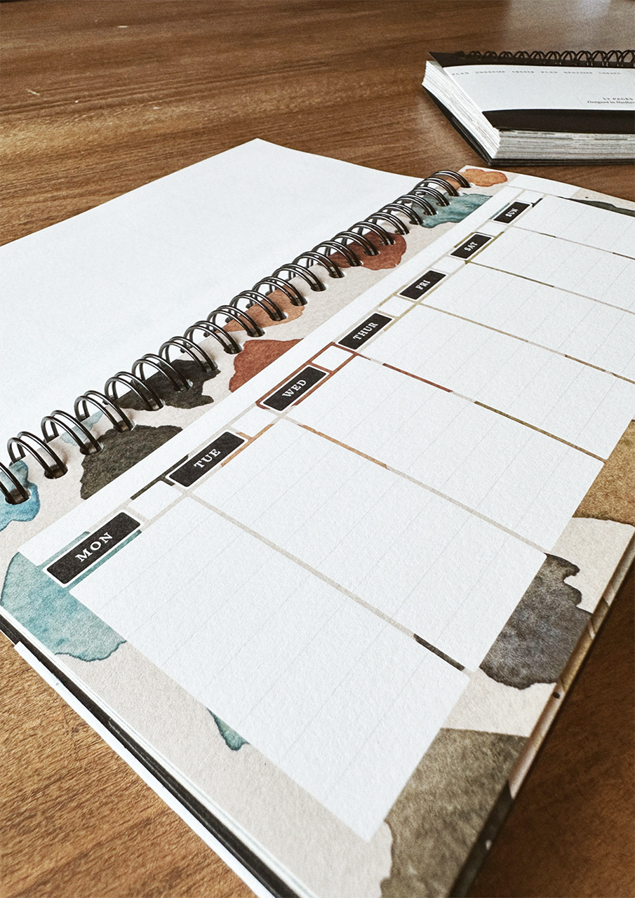 A desktop weekly planner, displayed on a wooden surface.