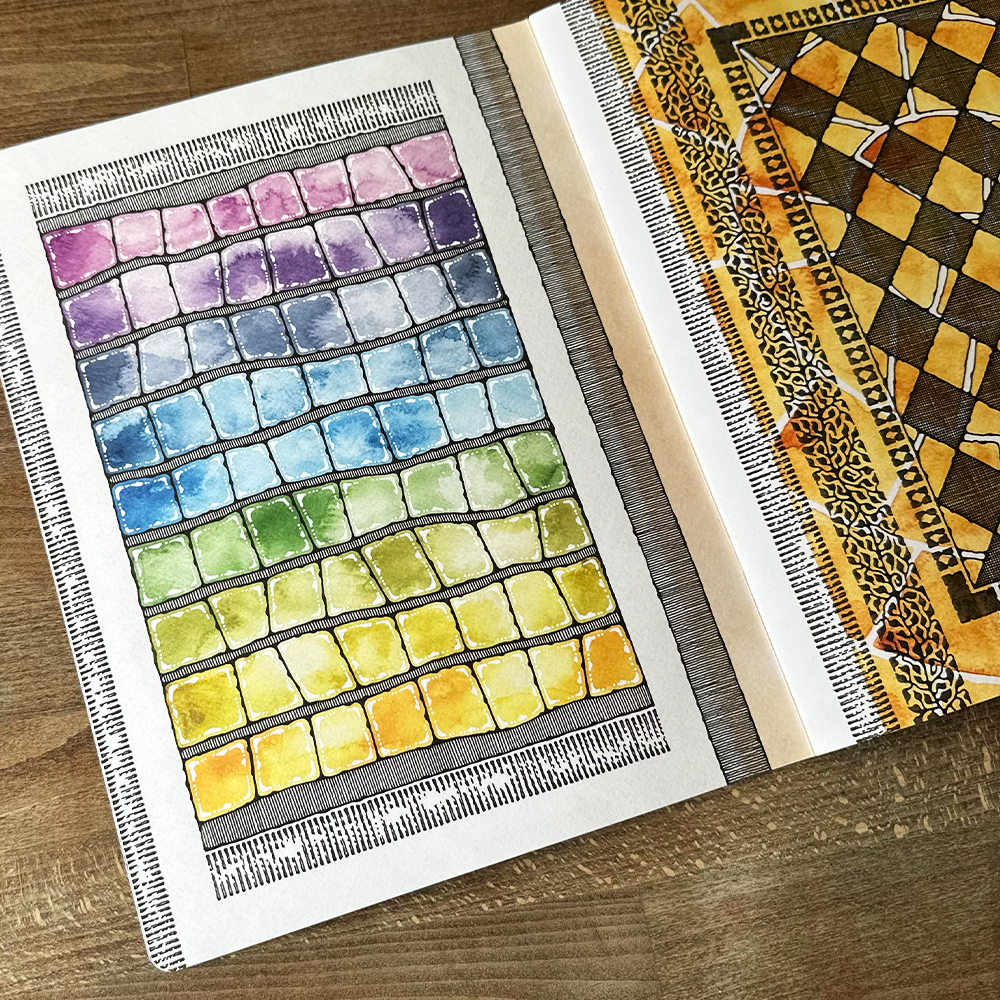 Color swatch book with watercolor color samples on a wooden surface