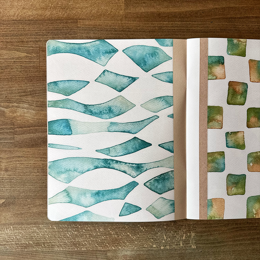 Open notebook with watercolor pattern on a wooden surface