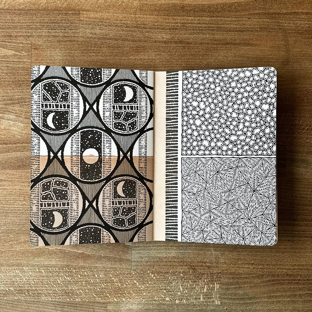 Two black and white patterned pages on a wooden surface