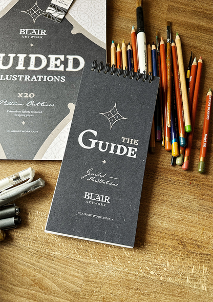 Two Guided Illustration books with pencils and pens in background