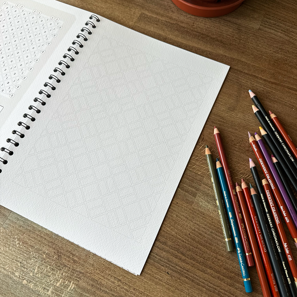 Open notebook with a set of colored pencils on a wooden surface