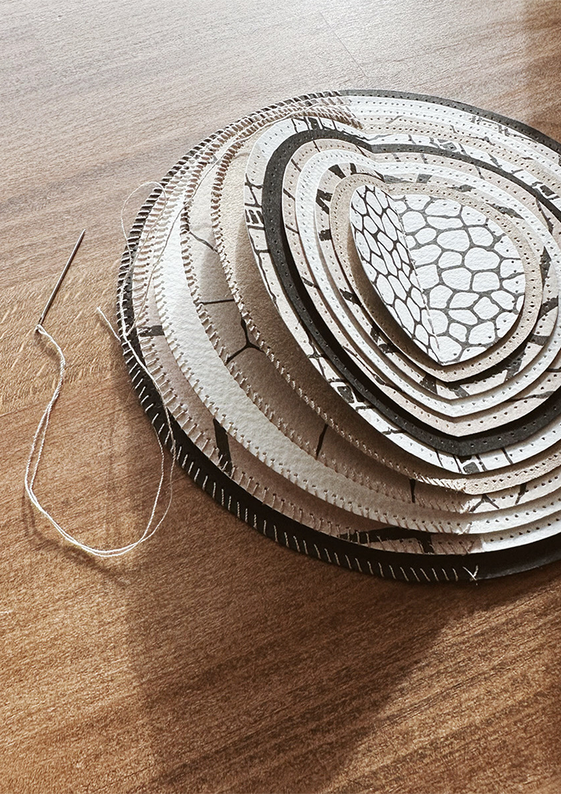 A framed hand-stitched artwork depicting a large circular paper moon on wooden table
