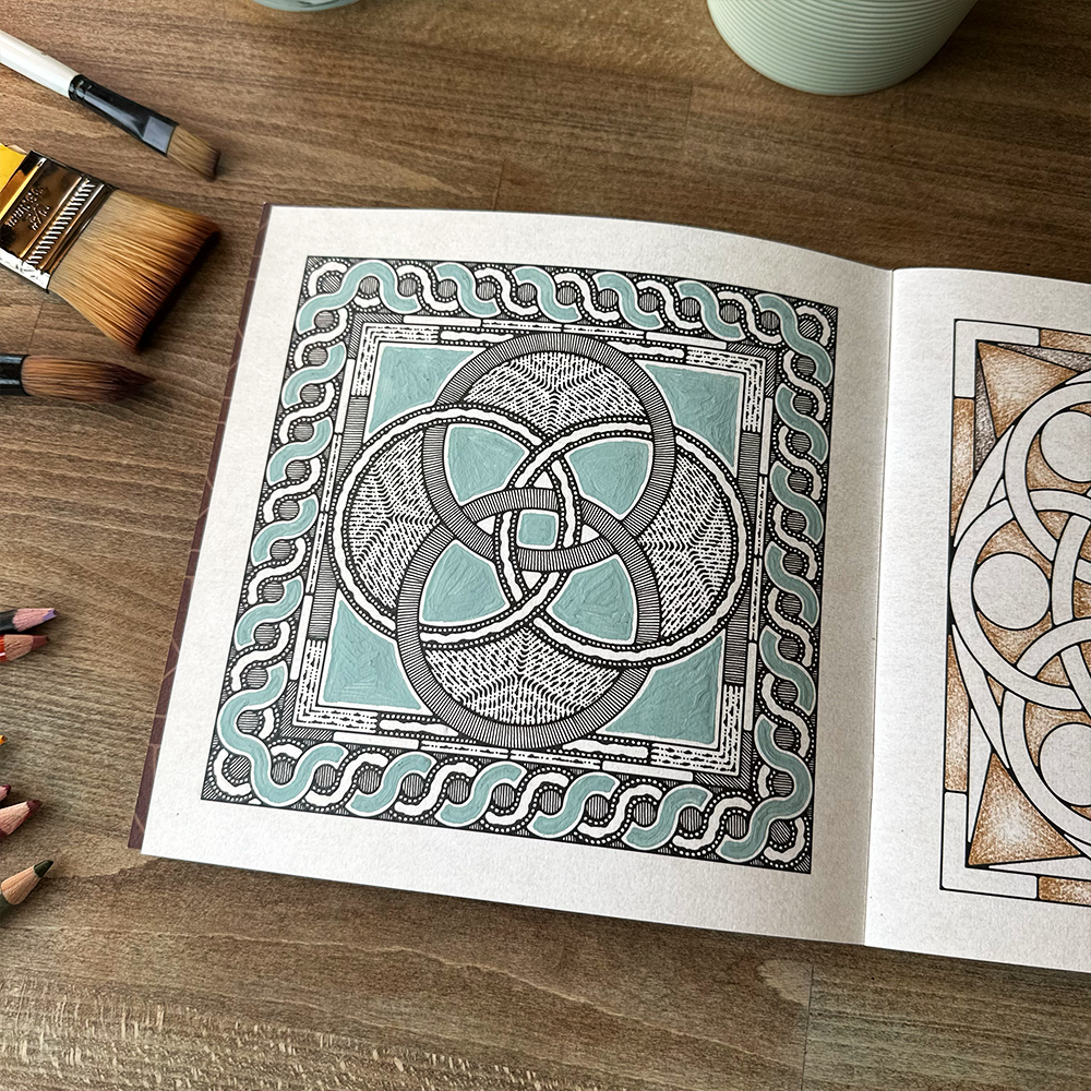 Coloring book open to a page with Celtic knot design on a wooden table.