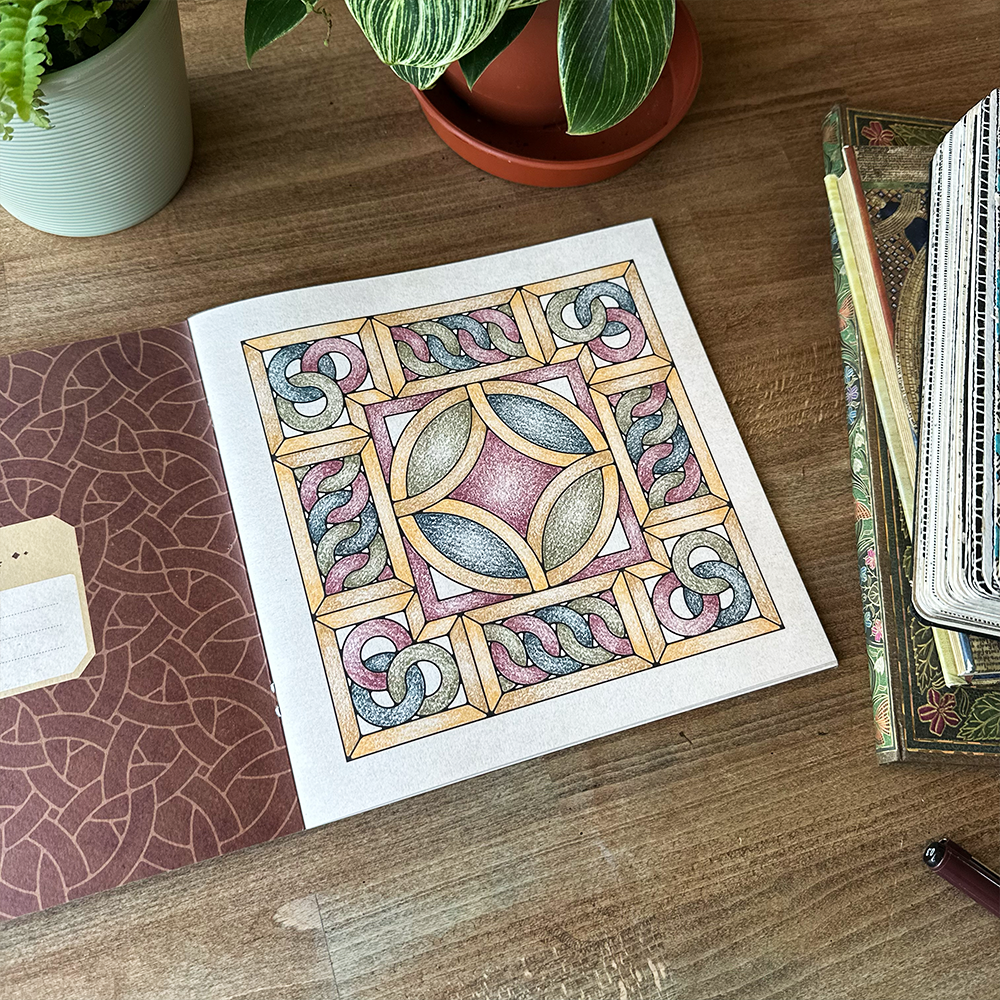 Decorative page with geometric pattern on a wooden surface with plants and books.