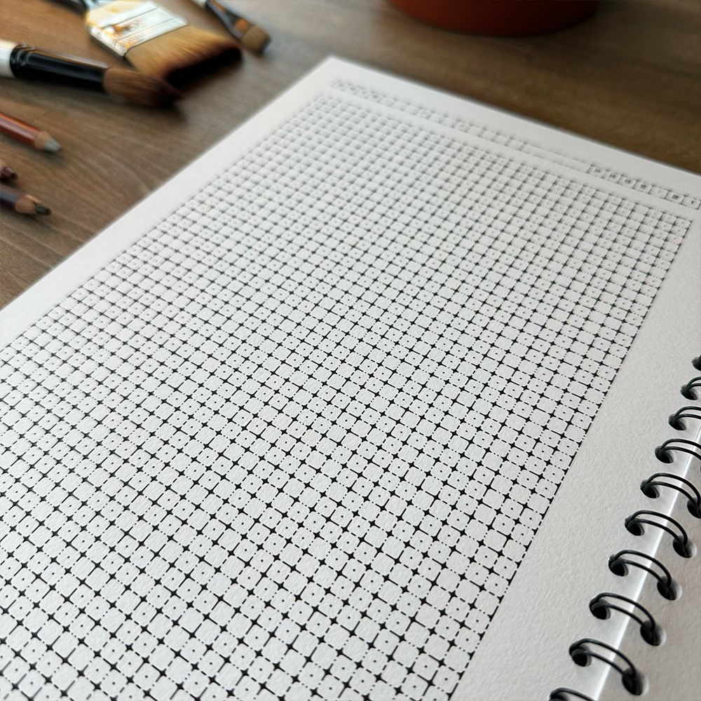 Grid notebook page on a wooden surface with art supplies