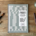 Peaceful Pixels mindfulness coloring book on a wooden surface with pens.