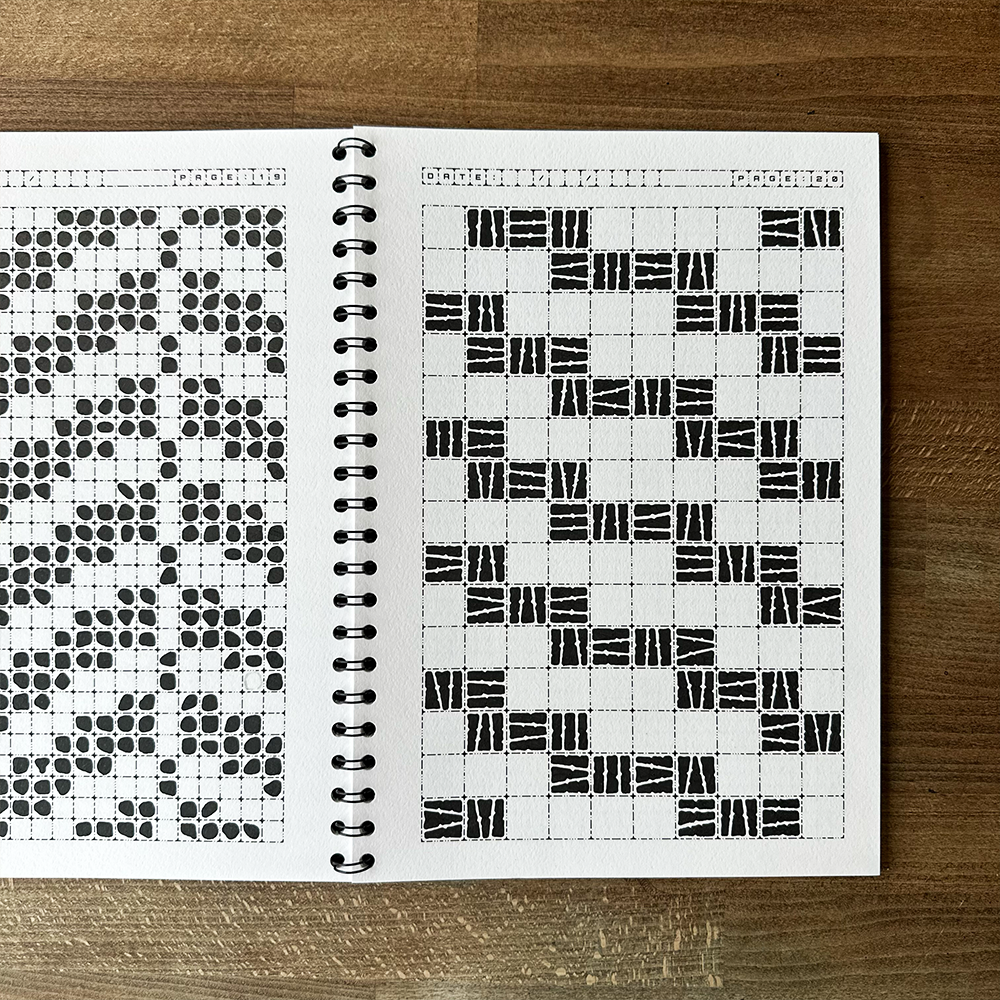 Spiral-bound notebook with black and white patterned pages on a wooden surface