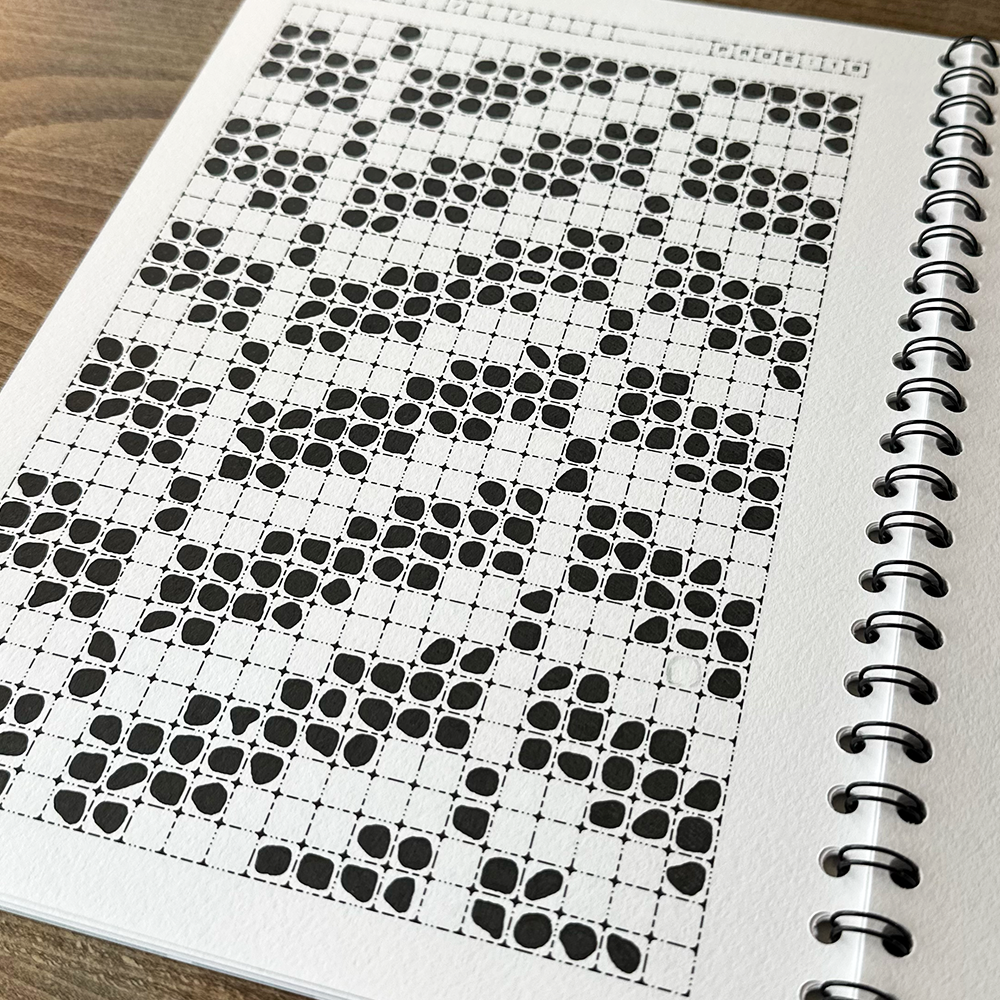 Spiral-bound notebook with a black and white pattern on a wooden surface