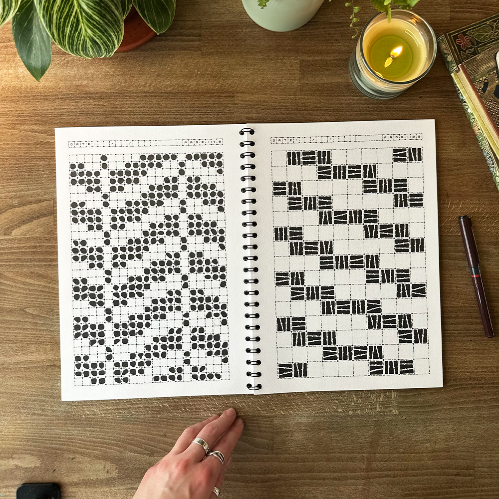 Spiral-bound notebook with black and white geometric patterns on a wooden surface.