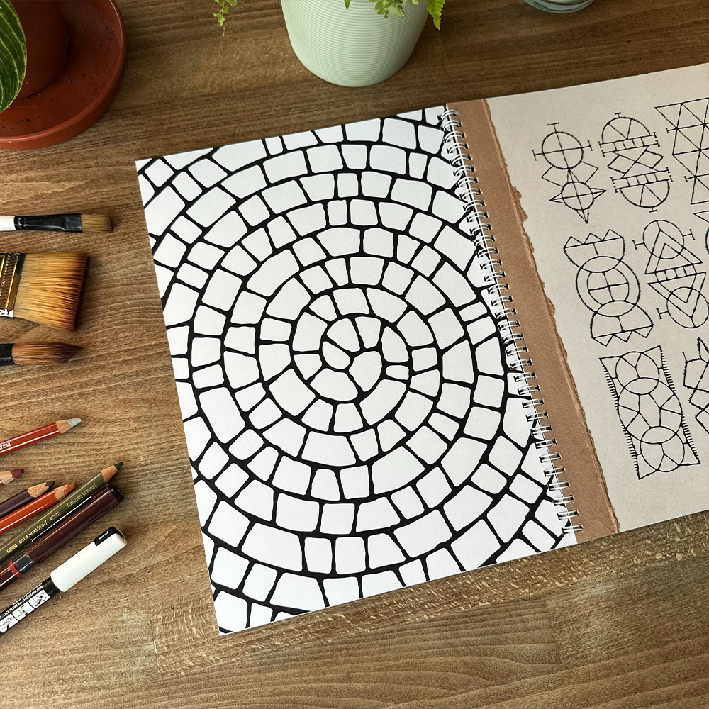 Notebook with a spiral binding on a wooden surface with art supplies