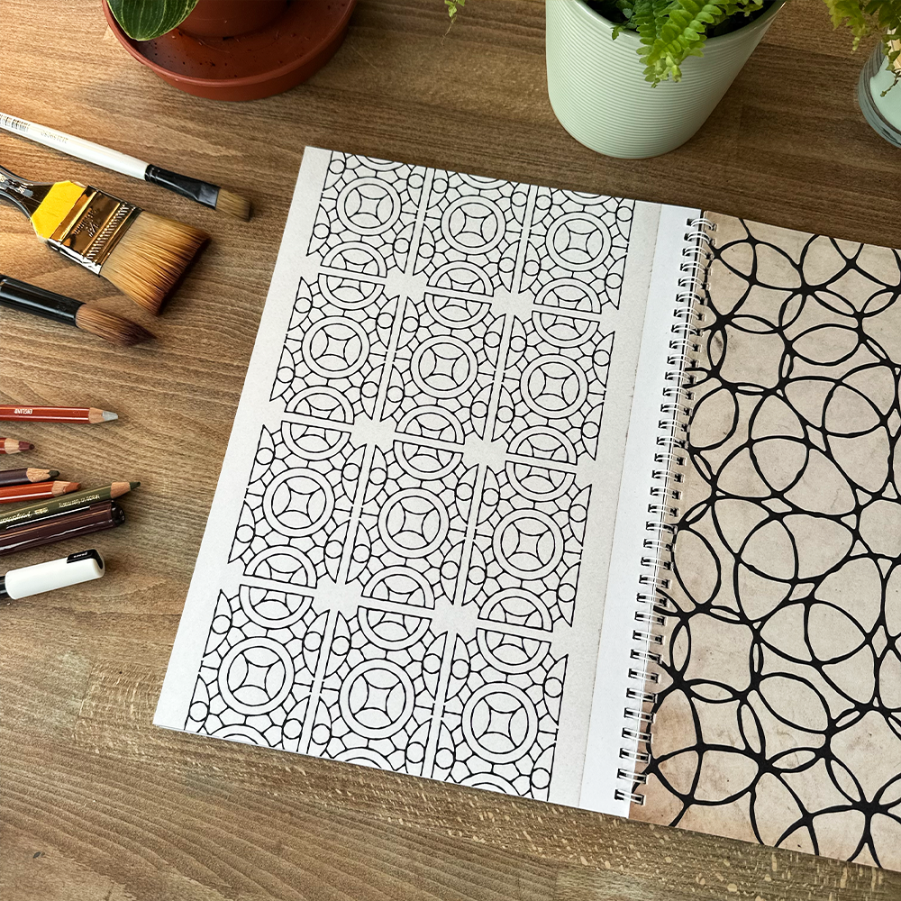 Coloring book with geometric patterns on a wooden table with art supplies.