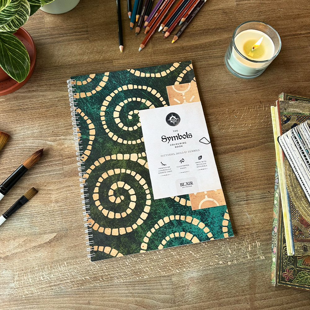 Notebook with spiral design on a wooden table with art supplies