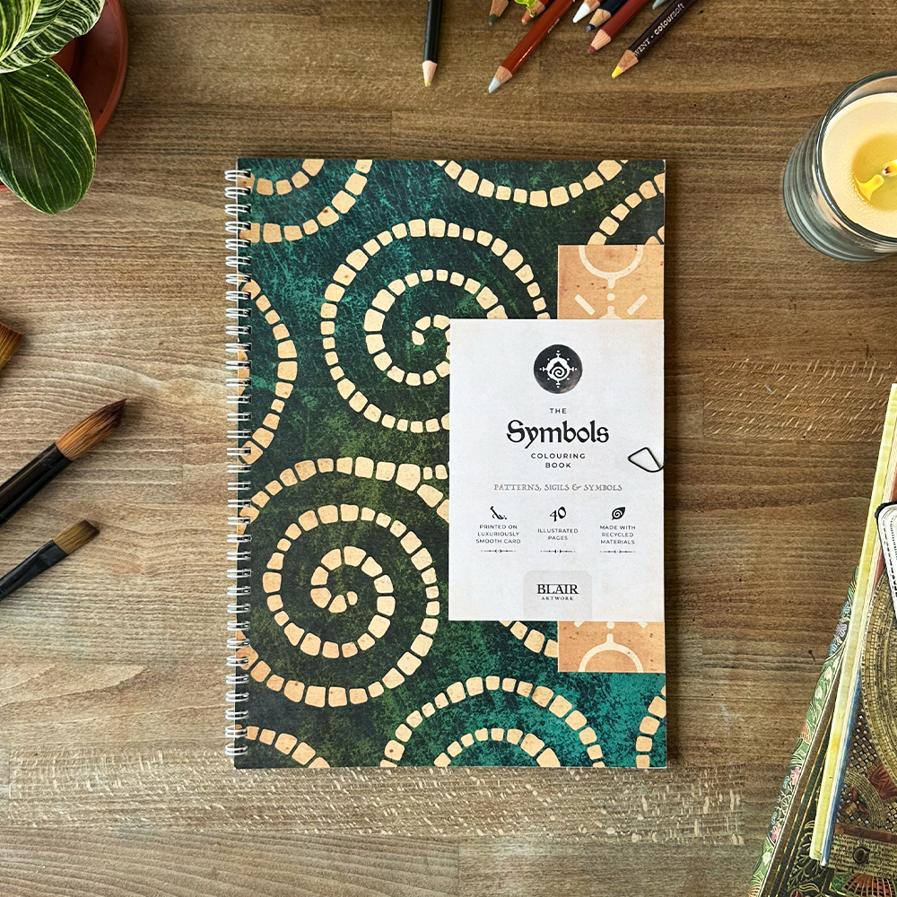 Coloring book with spiral patterns on a wooden surface with art supplies.