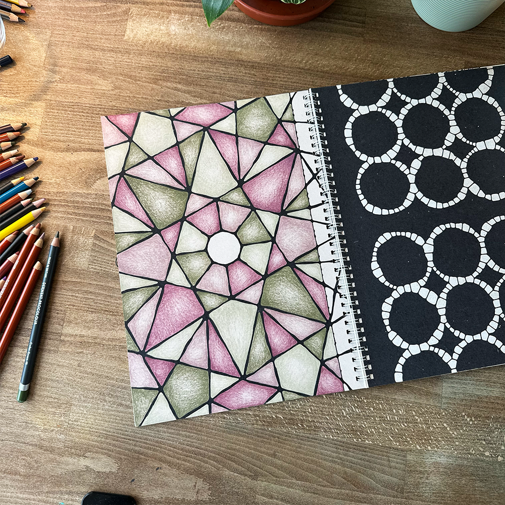 Two patterned notebooks on a wooden surface with colored pencils.