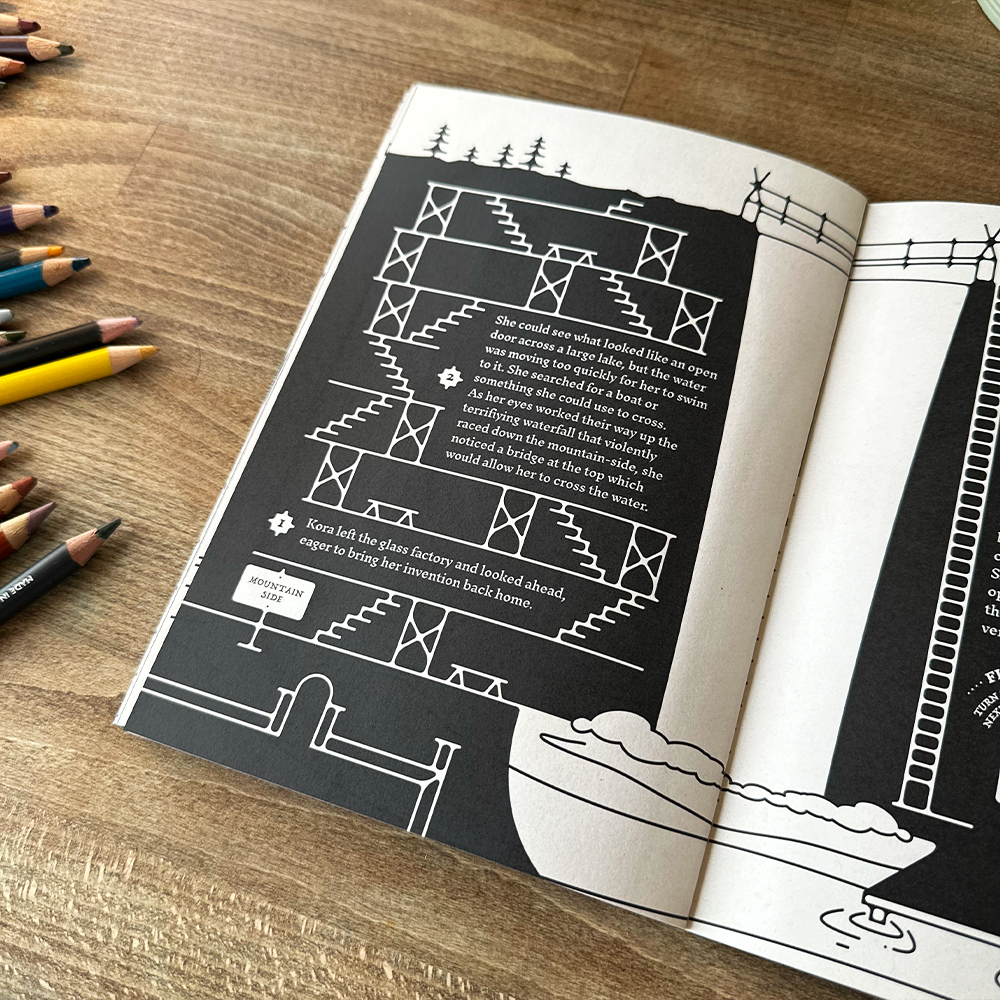 Open book with black and white illustrations on a wooden surface with colored pencils.