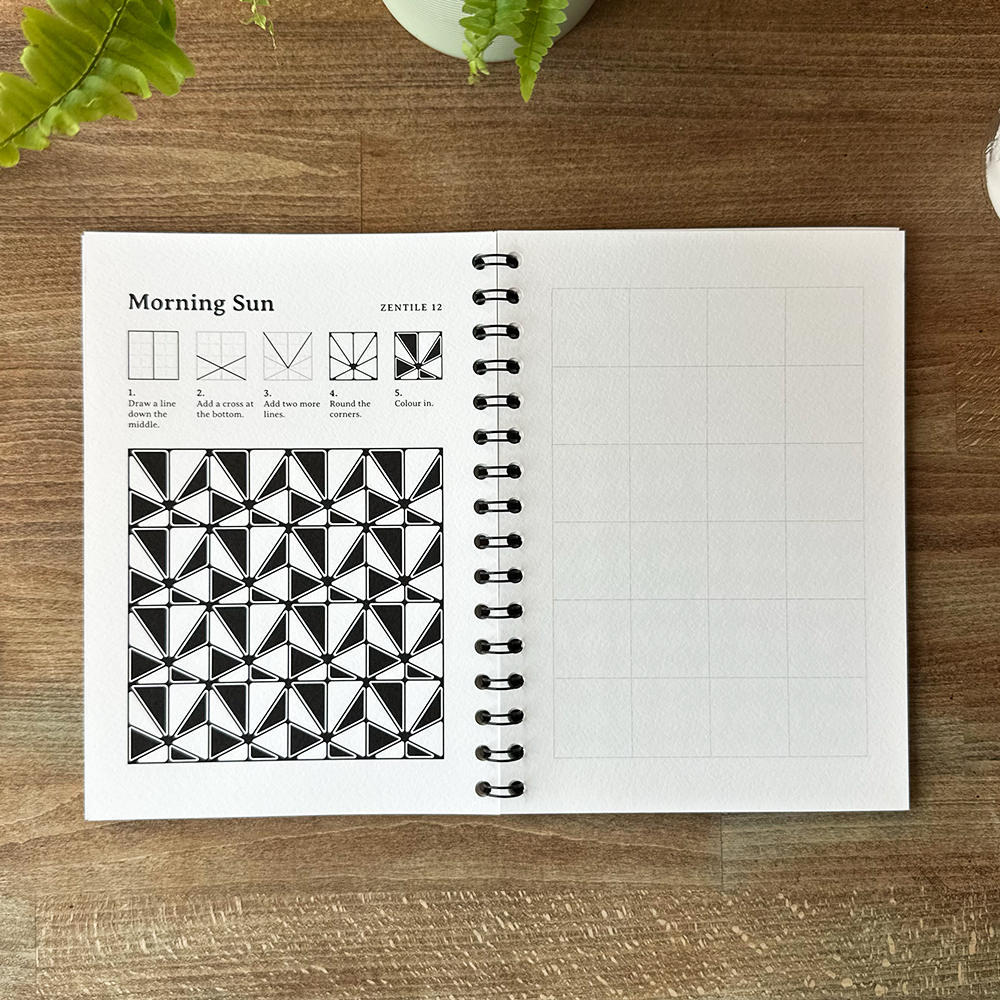 Open notebook with geometric design and instructions on a wooden surface