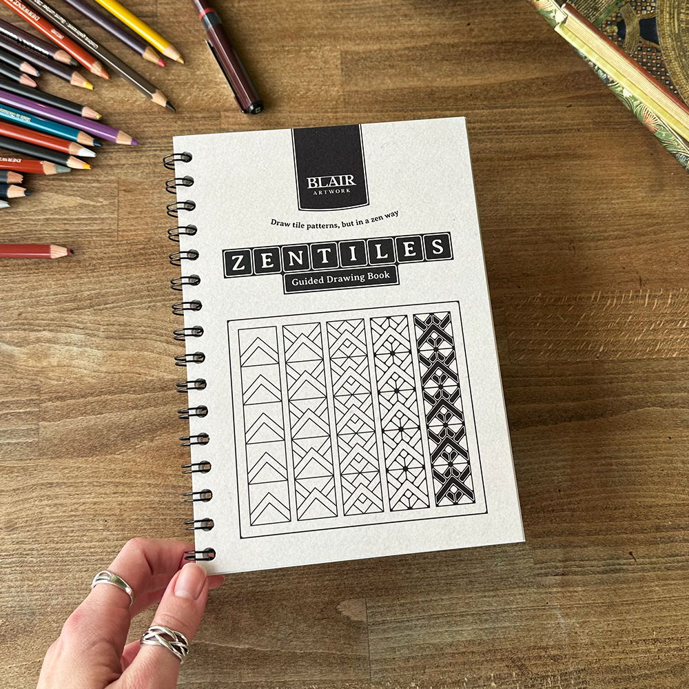 Zentiles guided drawing book by Blair Artworks on a wooden surface with colored pencils.