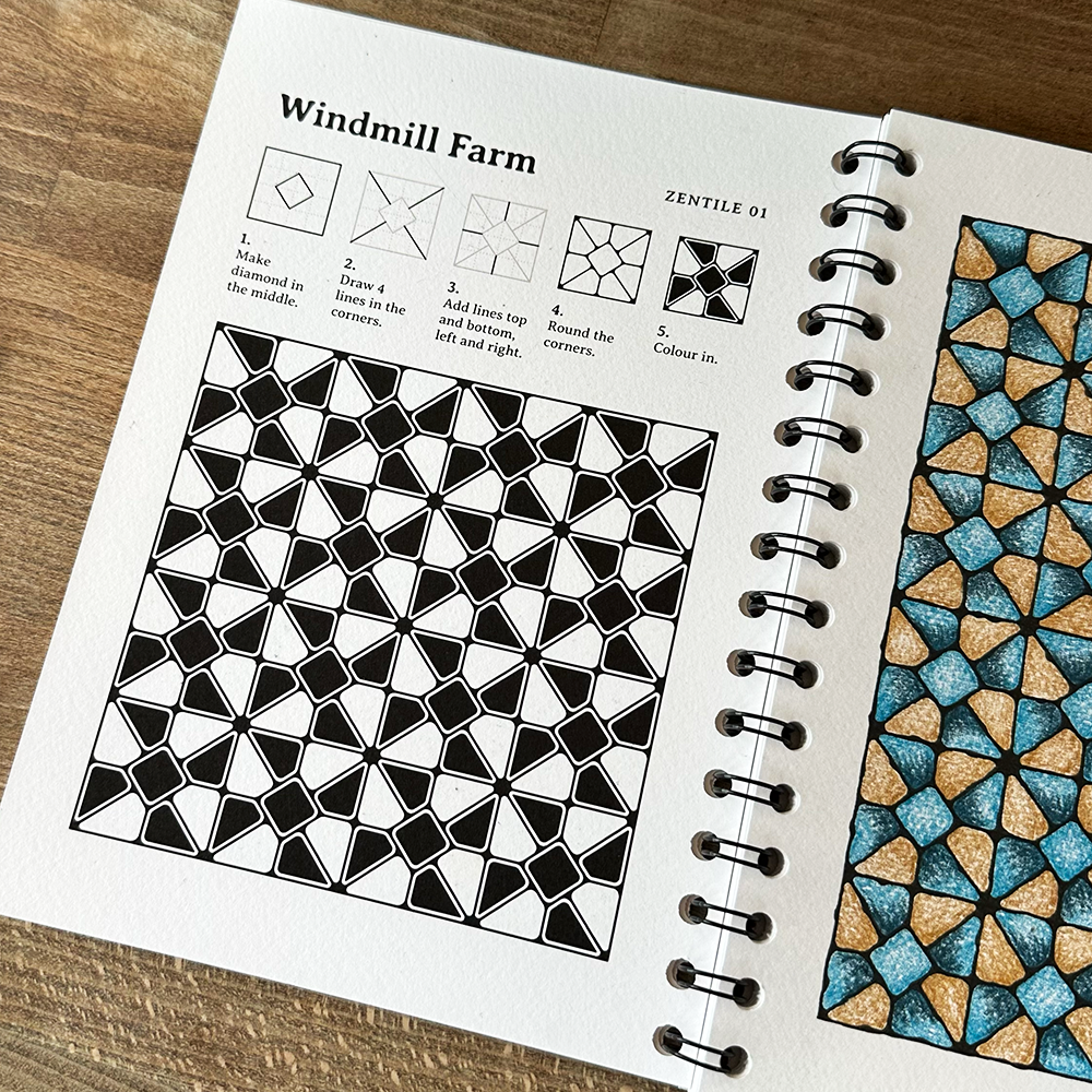 Spiral-bound notebook with geometric pattern instructions and examples on a wooden surface