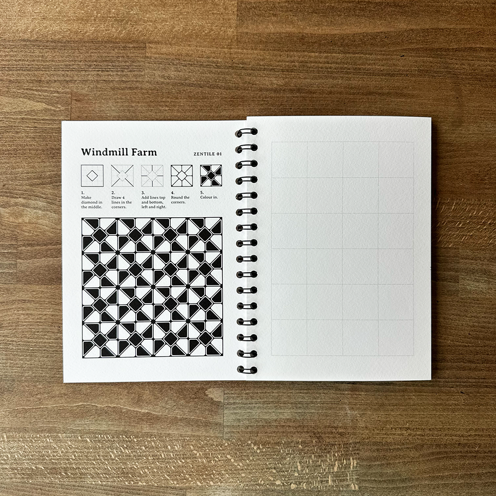 Open notebook with geometric pattern and text on a wooden surface